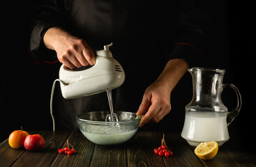 Preparation of a cocktail with pineapple juice and fruits using an electric hand mixer. Refreshing drink by the hands of the chef in the kitchen