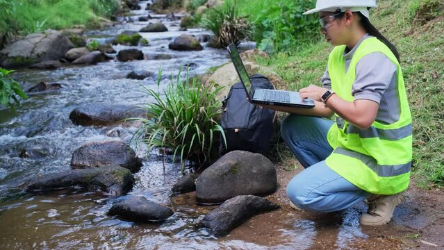 Environmental engineers inspect water quality at natural water sources and record the data on laptop computers. Woman scientist and environmental issues. World environment day concept.