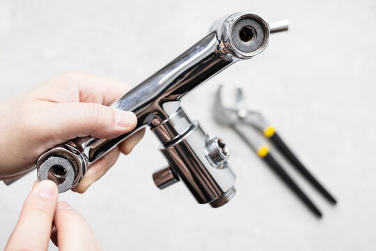 top view of plumber installs paronite gasket in shower faucet closeup and adjustable wrench on concrete board in background