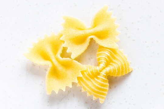 few uncooked farfalle pasta pieces on gray plate close up