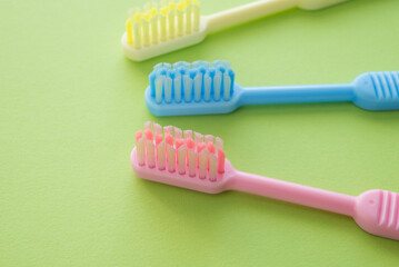 Colorful toothbrush on green background copy space. Dental care concept.
