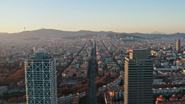 Aerial panoramic view on Barcelona from behind of Torre Mapfre and Hotel Arts towers. Camera flying backward showing Marina street running to Sagrada Familia church, residential and business districts