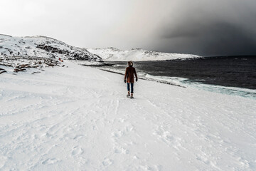 Man walking on the snow near the sea in mountain area