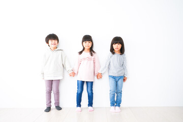 Obraz premium 壁に並ぶ3人の子どもたち