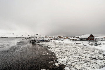 View on snowy village near the sea in dramatic sky