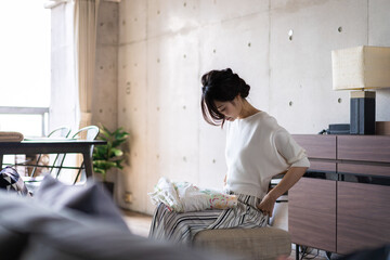 家で洗濯物をたたむ若い女性