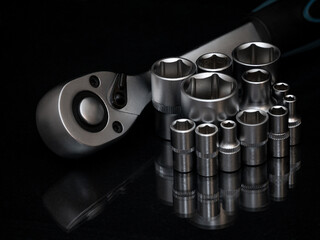 Ratchet wrench. Set of stainless steel hex sockets on shiny black surface. Universal professional...