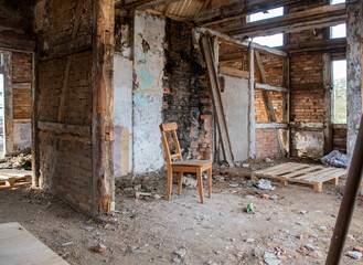 Fototapeta na wymiar Ein alter Holzstuhl steht in einem zerfallenem Bauernhauses Ruine Lost Place 
