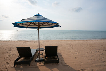Two wooden chairs and umbrella on stunning sunshine tropical beach with sun light.