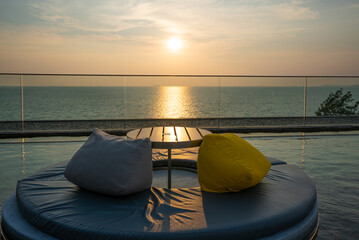 cushions seat sofa in Swimming pool at luxury villa on sea view sunset sky.
