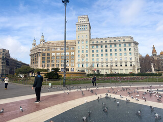 Tourists visiting Catalonia square crowded with pigeons in Barcelona