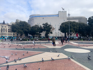 Tourists visiting Catalonia square crowded with pigeons in Barcelona