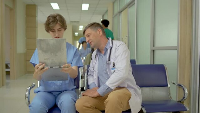 Doctor explaining patient diagnosis to one of female medical student for advice. about the sickness of the patient in hospital waiting area. In the Background Patient and doctor