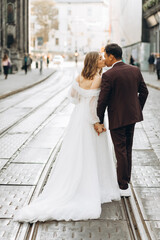 An international wedding couple, a European bride and an Asian groom walk around the city together.