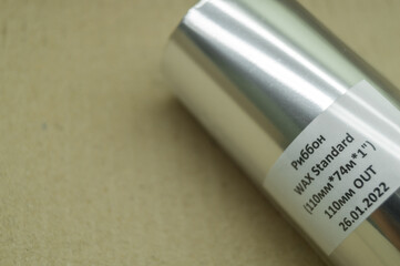 Packed thermal transfer ribbon. TTR wax standard. Wax thermo ribbon on cardboard reel for barcode. Supply material for printing industry. Selective focus. Russian text: Ribbon