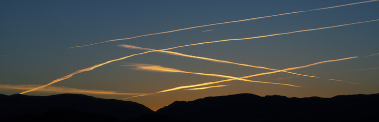 Image of condensation trails or contrails shown against a dawn sky in the Mojave Desert.