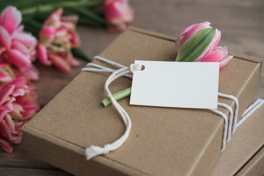 Mock up tag and kraft gift boxes decorated with flowers. Preparation of gifts for mother's day, birthday, women's holiday. Gift wrapping idea