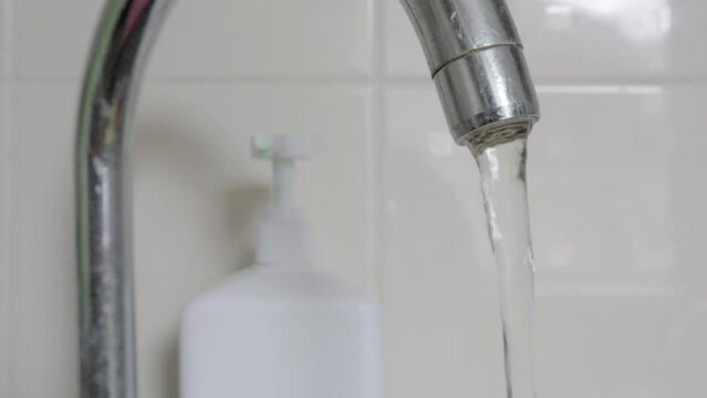 Close-up of drinking tap water flowing from a faucet. Designing a faucet in the kitchen or bathroom. The concept of water saving and water consumption, tariff and price of water.