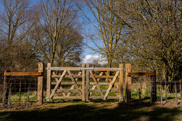 Private farm land fenced off by a large gate with a private keep out sign showing no access to the rural pathway