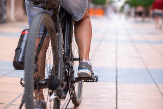 Close up on casual woman's legs while running her electro bicycle in urban street