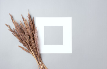 White photo frame with a pampas bouquet on a grey background. Copy space, flat lay. 