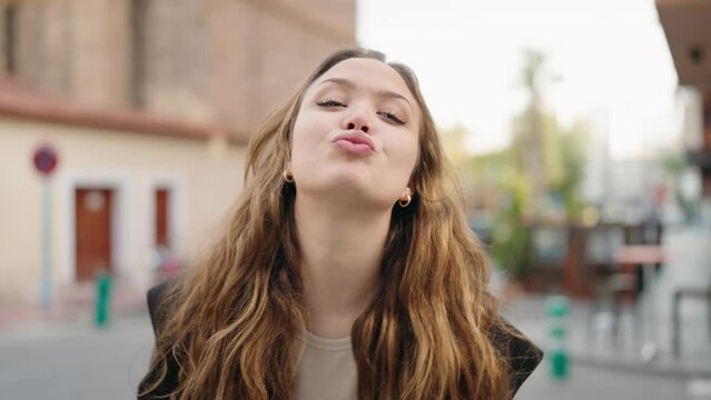 Young hispanic woman smiling confident kissing at street