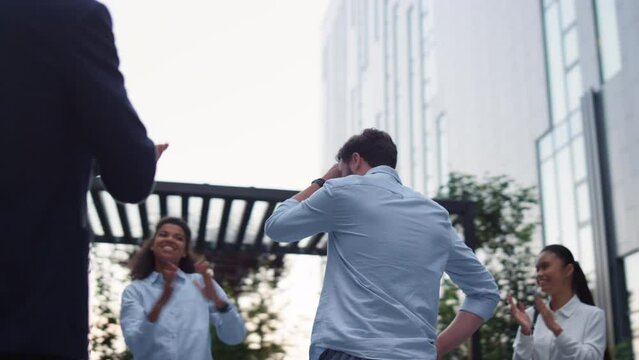 Work team applause leader at office building. Happy workers praise employee.