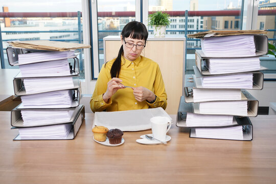 Sekret&auml;rin feilt an ihren Fingern&auml;geln, w&auml;hrend sich die Aktenberge neben ihr auft&uuml;rmen