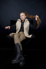 girl sitting on a chair holding her hair on a black background