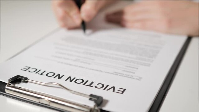 eviction notice. A person's hand signs a document. A warning. He is deprived of property, a mortgage on a mortgage. Unemployment and crisis.