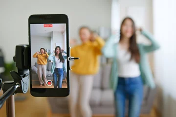Fotobehang Asian young woman with her friend created her dancing video by smartphone camera together. To share video on tiktok social media application © Nattakorn