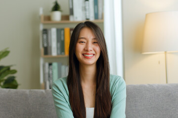 Portrait of young Asian woman look at camera and smile at home.