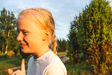 A little blonde girl walks in the countryside in a warm summer day.