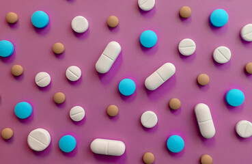 Colored pills, tablets on a pink background