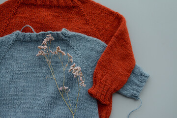 Various colors and sizes handmade baby sweaters, two items done and one in progress 