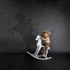 dziecięce marzenia do spełnienia, chłopiec na koniu marzy o byciu kowbojem - obrazy, fototapety, plakaty