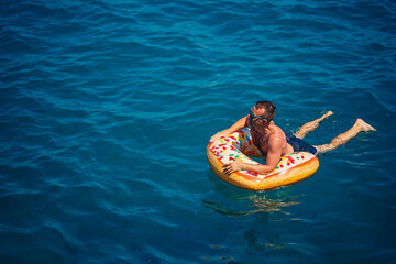 Young man on an inflatable ring in the sea resting and swimming on a sunny day