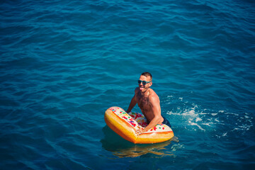 Young man on an inflatable ring in the sea resting and swimming on a sunny day