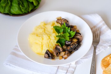 Healthy vegan lunch, soft-boiled mashed potatoes, fried mushrooms with onion and croutons, bread. Top view. Fresh dill, parsley, spinach in the frame. Slavic traditional meal on a light natural linen.