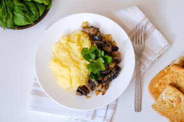 Healthy vegan lunch, soft-boiled mashed potatoes, fried mushrooms with onion and croutons, bread. Top view. Fresh dill, parsley, spinach in the frame. Slavic traditional meal on a light natural linen.