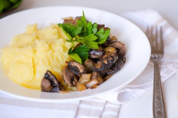 Healthy vegan lunch, soft-boiled mashed potatoes, fried mushrooms with onion and croutons, bread. Top view. Fresh dill, parsley, spinach in the frame. Slavic traditional meal on a light natural linen.