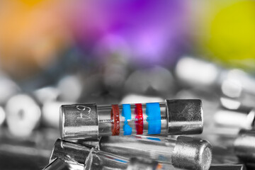 Closeup of small electrical fuses pile on blurry background with colored and white bokeh. Safety...