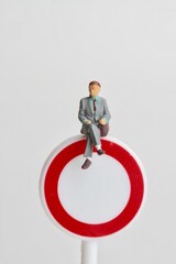 miniature figurine of a businessman sitting on an access ban sign