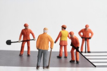 Miniature figurines of men at work with an old man looking at their work 
