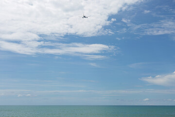 Passenger plane flying over blue ocean. Blue sky with white cloud background