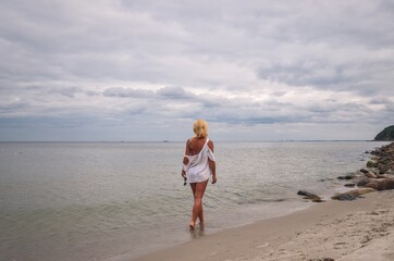 Holiday seaside session. Beautiful woman on the seashore looking to the horizon.