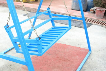 Colorful blue empty 'Swing' made with wood display with selective focus on a outdoor park.