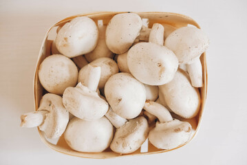Champignon mushrooms in a wicker basket on a white background