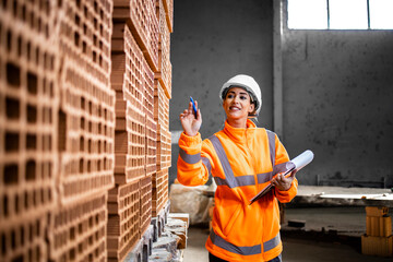 Industrial female worker checking inventory of bricks ready to deliver to the construction site.