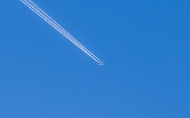 Fototapeta na wymiar White trail from a flying plane on a blue sky